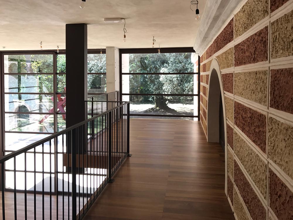 Wooden loft that follows a red and white brick wall and ends at an angle with a large window