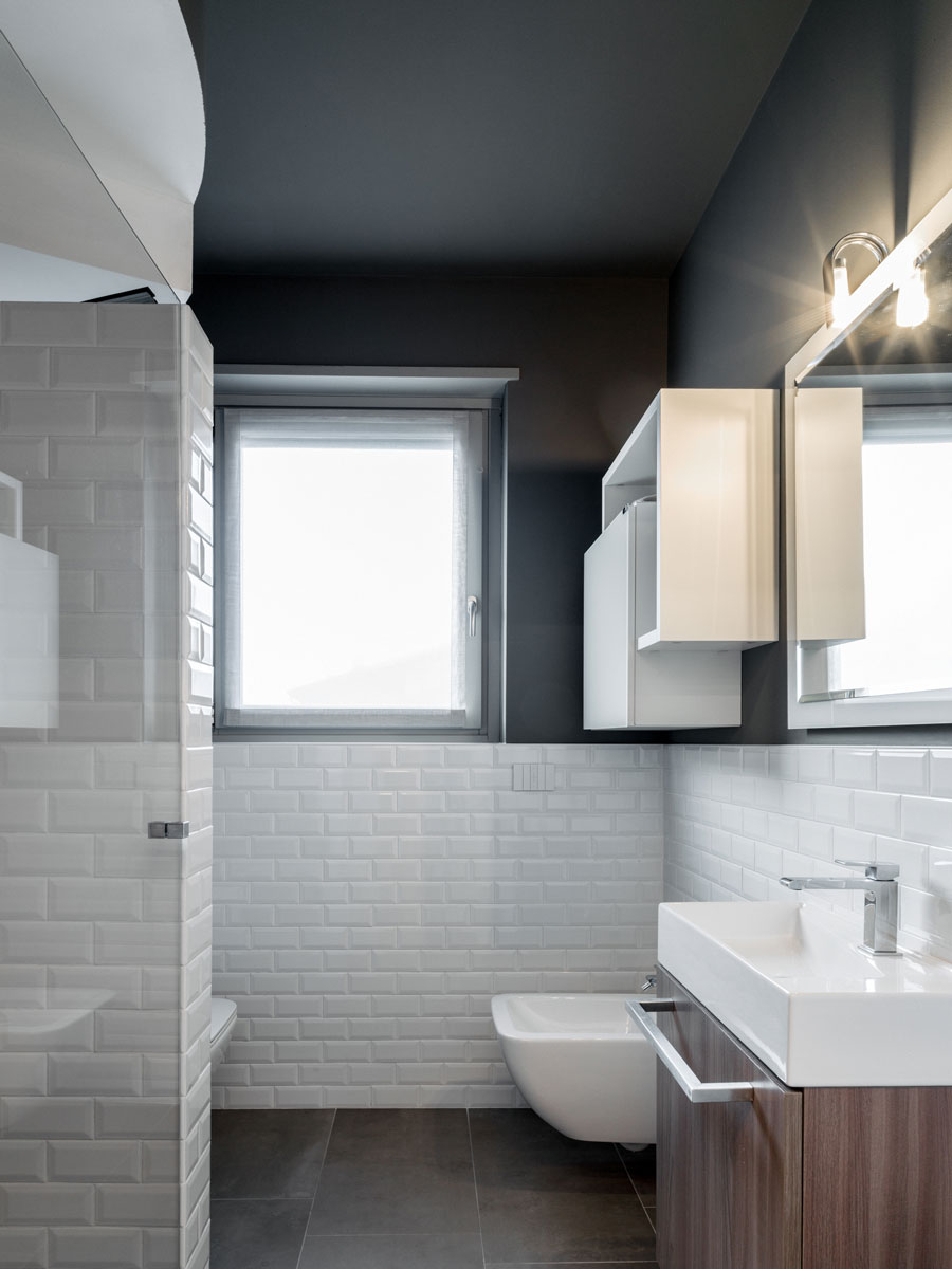 Bathroom with black walls and floors and white tiles and sanitary ware