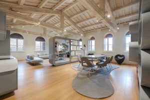 Open space con pavimento e soffitto in legno e arredamenti grigi