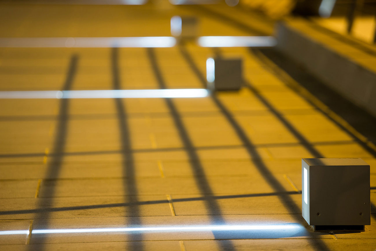 Metallic squares that project a beam of light onto the wooden floor