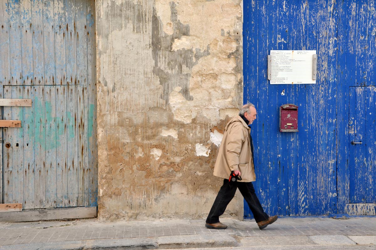 Anziano che passeggia lungo una via