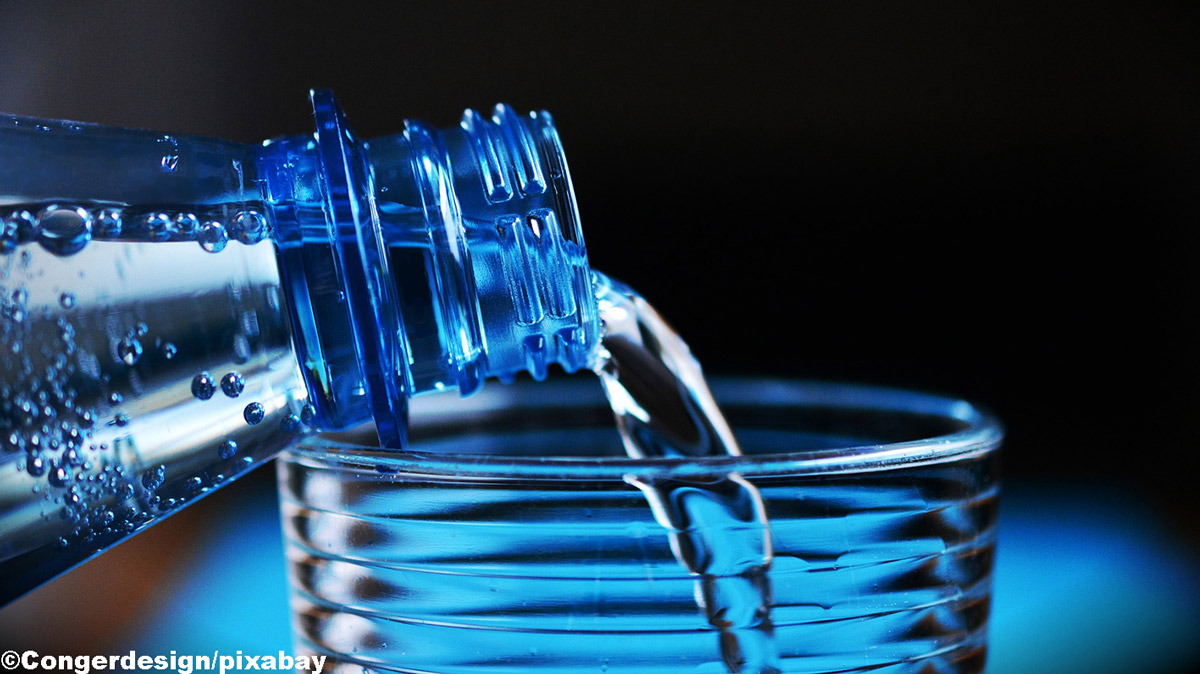 Acqua in bottiglia versata su un bicchiere