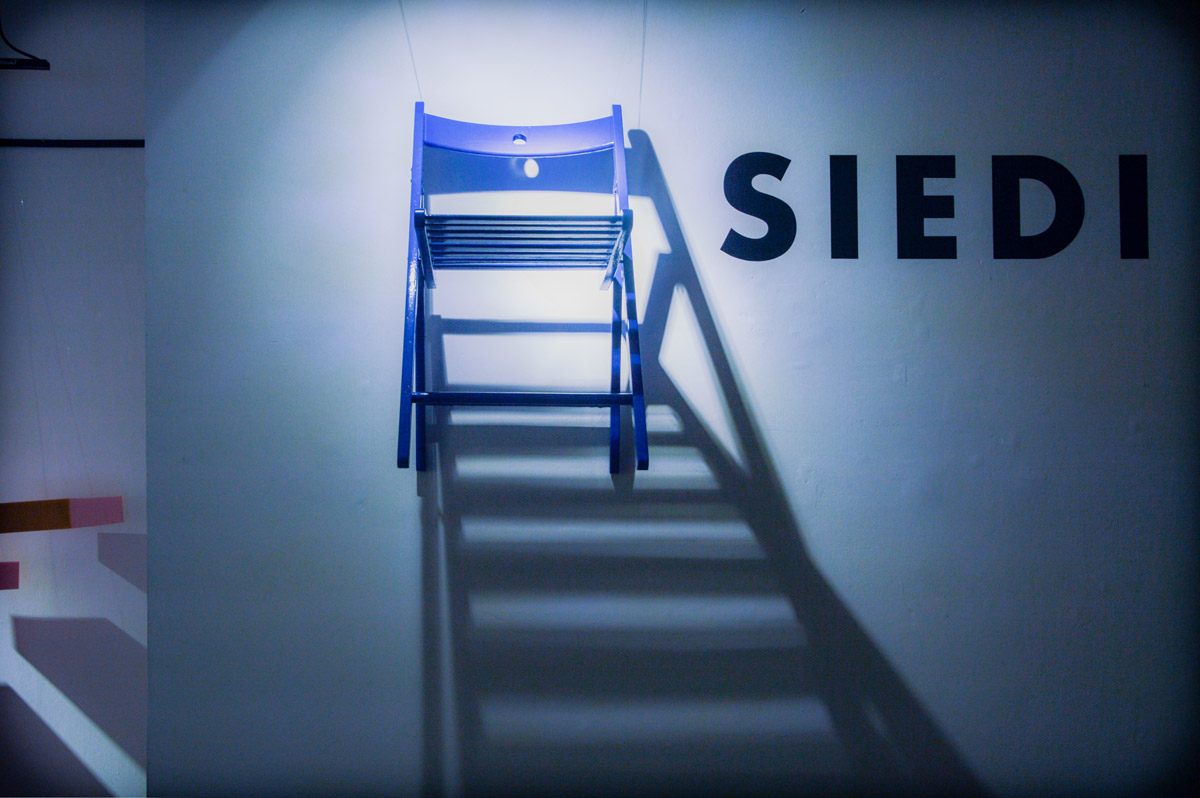 Suspended chair with wires with the word "Siedi"