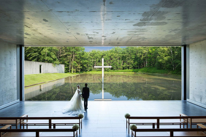 Coppia che si sposa in una chiesa con una vetrata che da su un lago