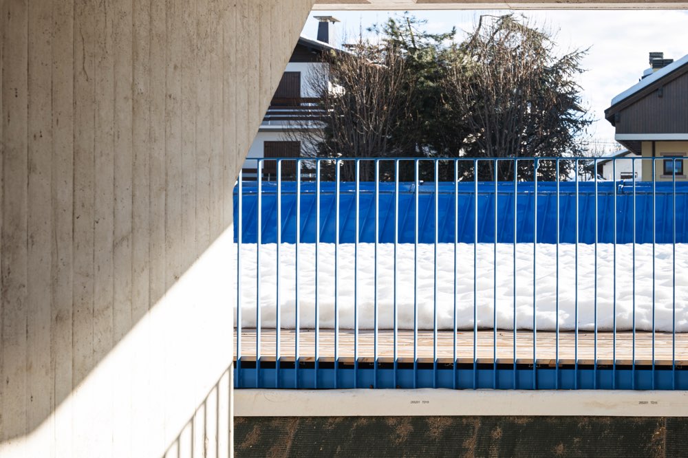 Ringhiera blu che corre lungo una terrazza con una pavimentazione in legno coperta di neve