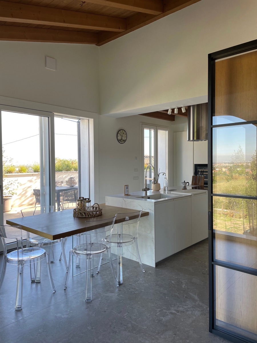 Bright kitchen and casual dining area with transparent seating and a cozy atmosphere in the TR House, from twoPIU architects