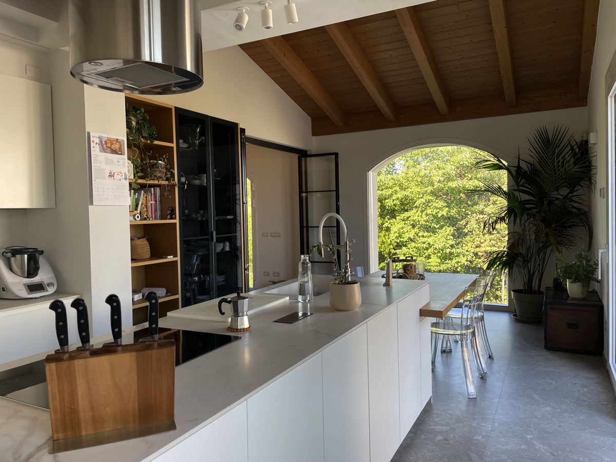 View of the large kitchen in the TR House, featuring transparent chairs and a marble center island, by twoPIU architects