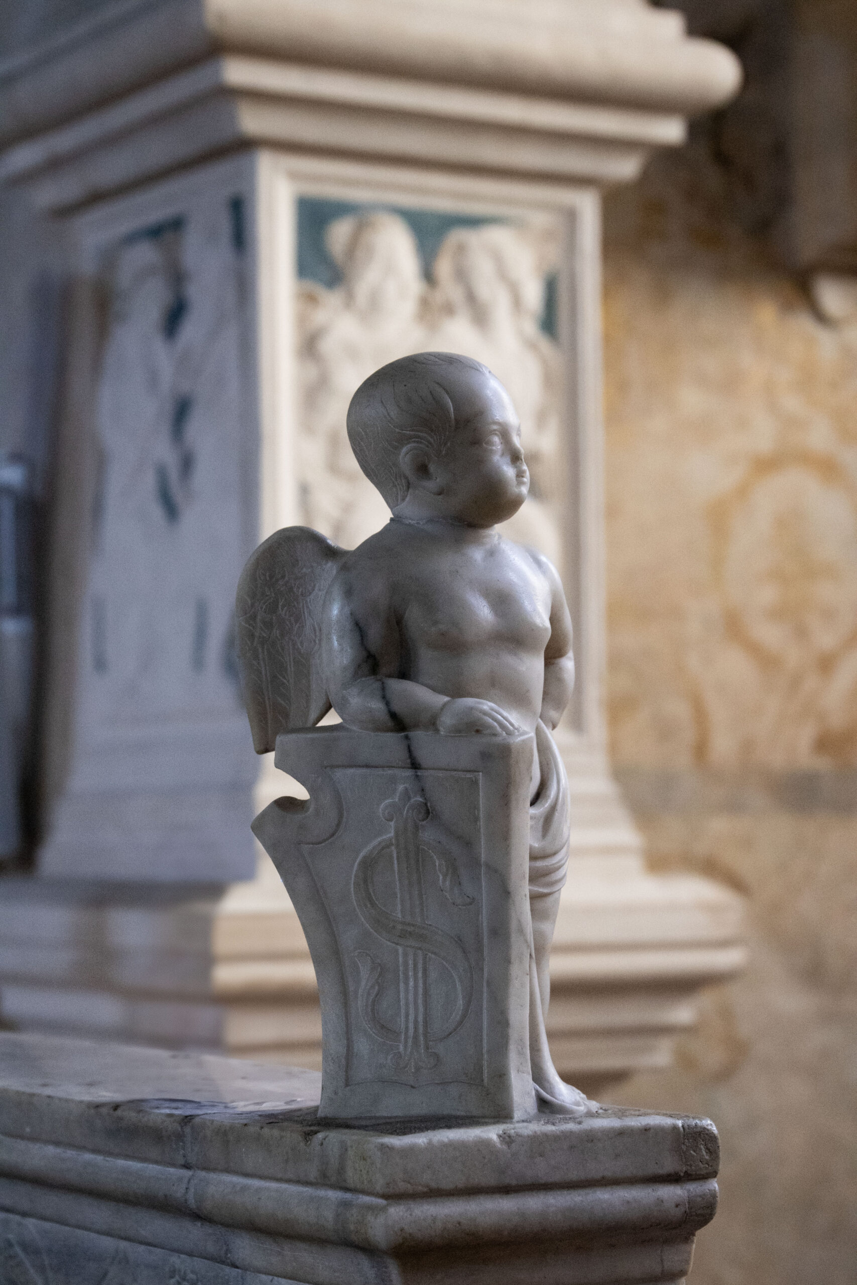 Statua in marmo di un cherubino con le ali, che simboleggia l'innocenza e gli attributi celesti.