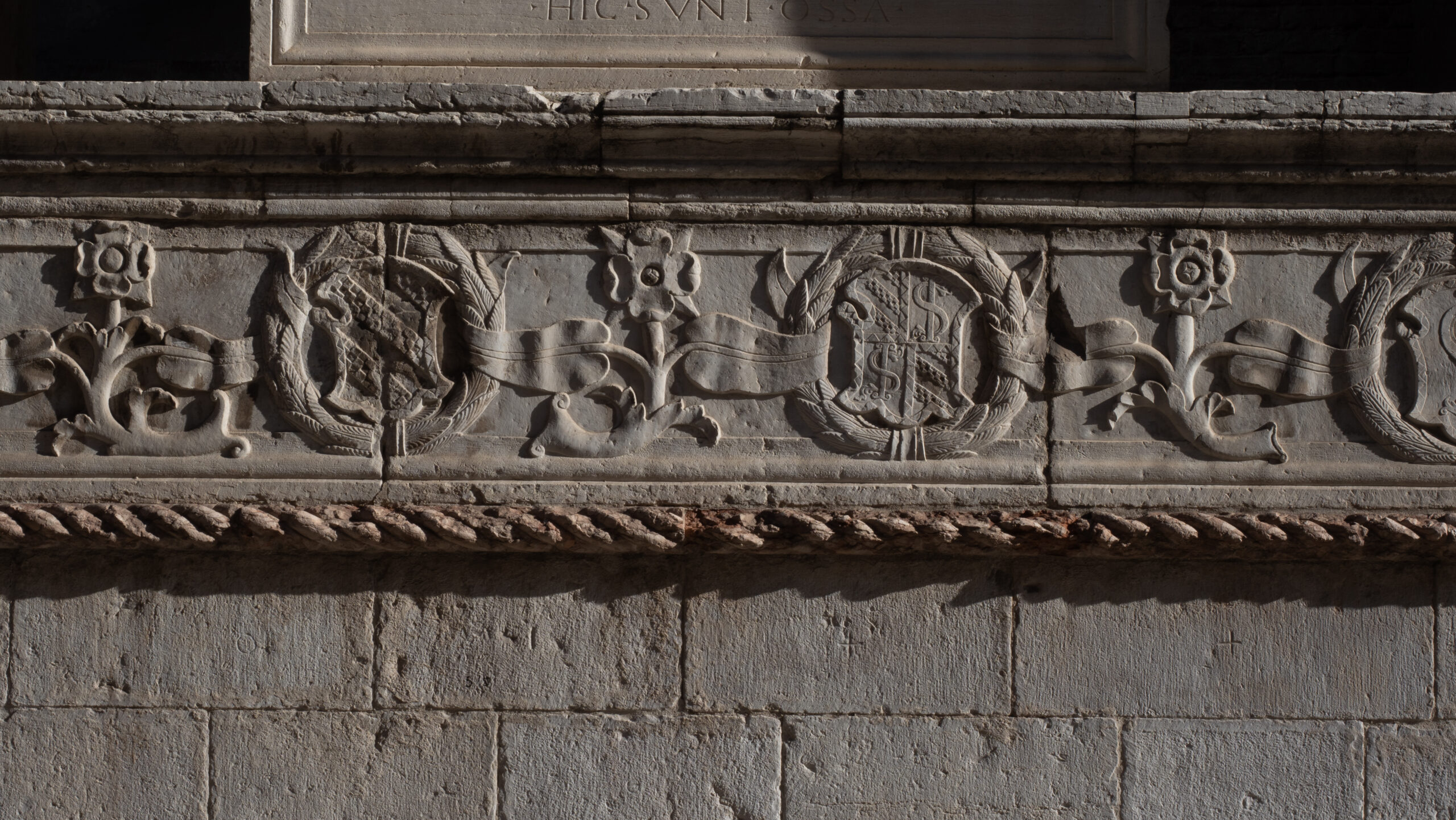 Primo piano di un arco romano con intricati intagli e iscrizioni storiche.
