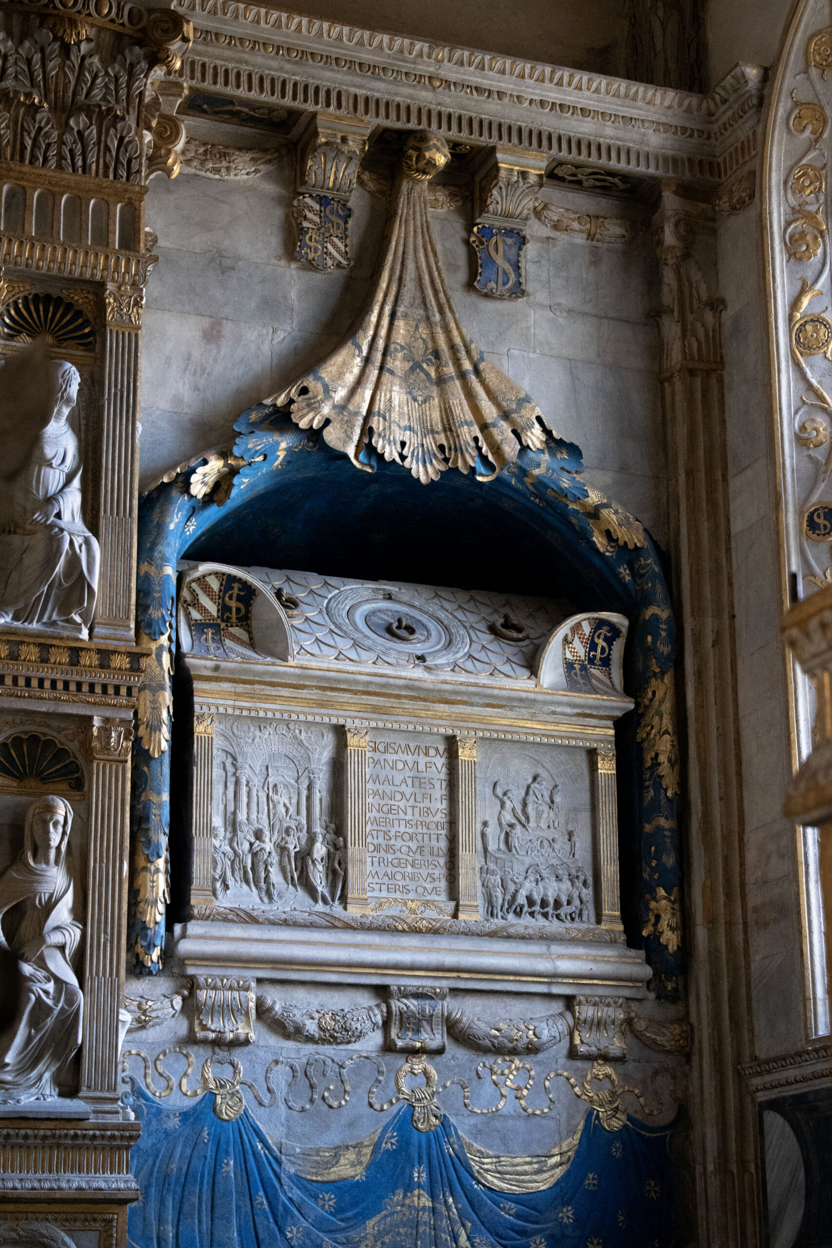 Altare rinascimentale ornato con drappeggi blu e oro ed elementi scultorei classici.