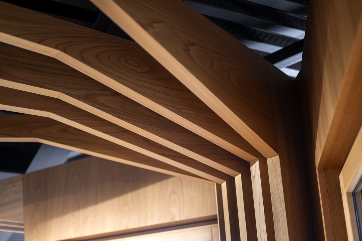 Dettaglio di una struttura in legno che ricorda i rami di un albero, con travi che si diramano dal centro verso l'esterno. La texture del legno e la luce naturale evidenziano i dettagli delle venature.
