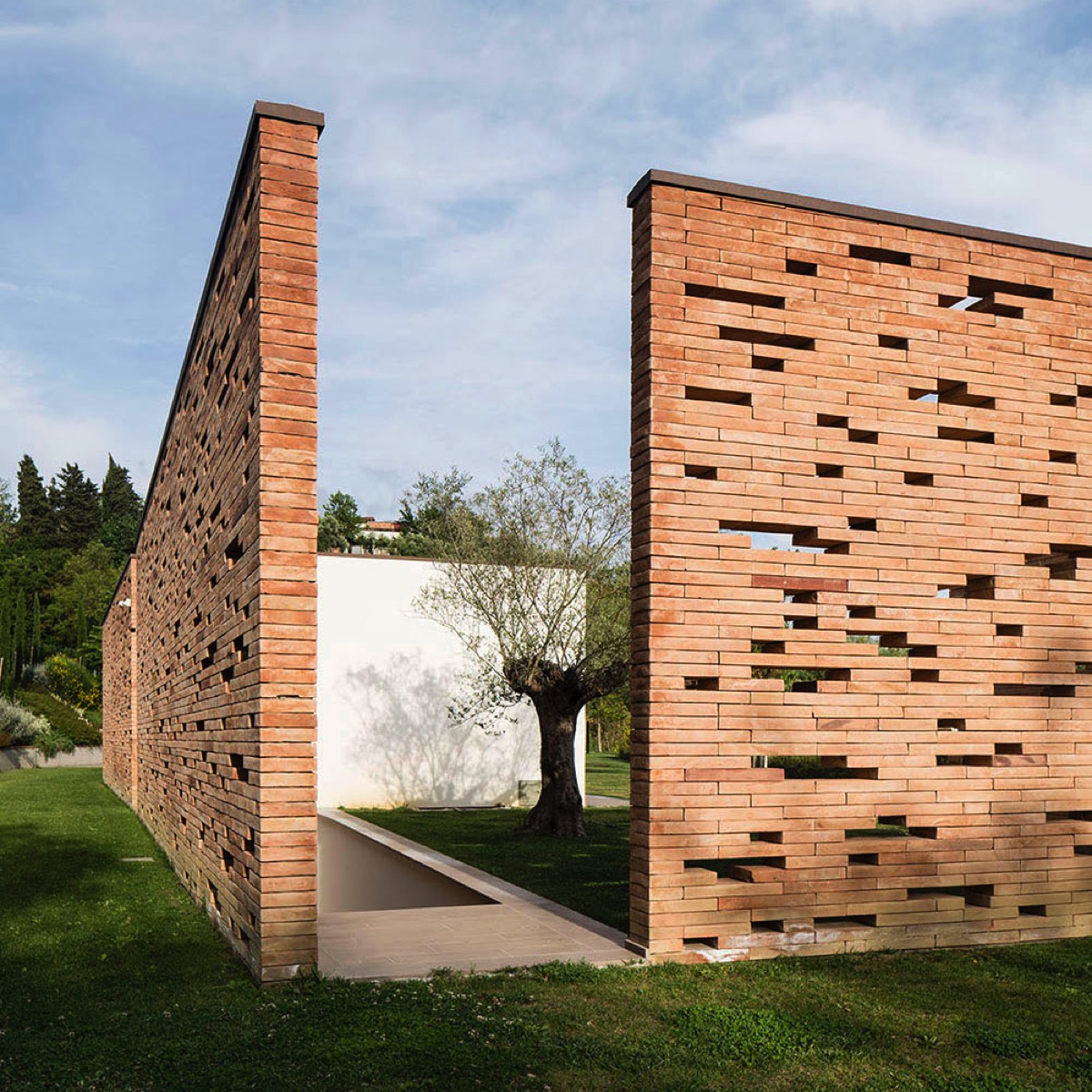 Vista esterna dell'abitazione privata a San Miniato, caratterizzata da un moderno muro in mattoni con aperture geometriche.