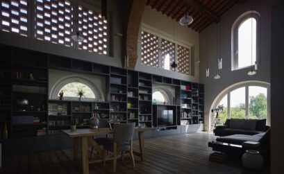 Interno dell'abitazione privata a San Miniato, con un design contemporaneo, grandi finestre ad arco e una libreria a tutta parete.