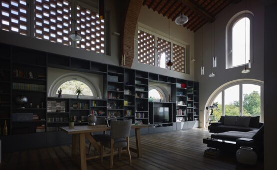 Interno dell'abitazione privata a San Miniato, con un design contemporaneo, grandi finestre ad arco e una libreria a tutta parete.