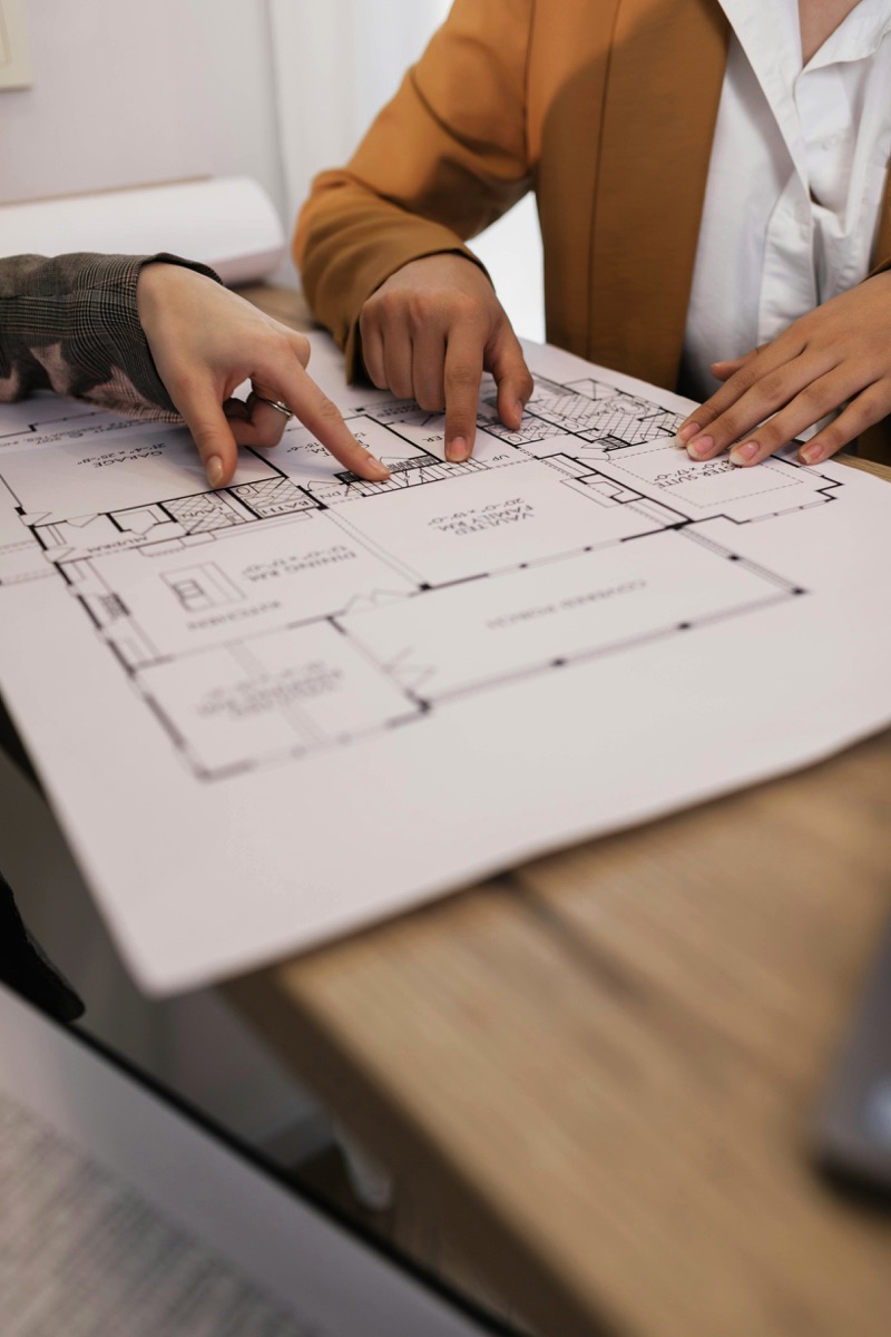 Due persone che indicano la pianta di un edificio durante una fase di progettazione