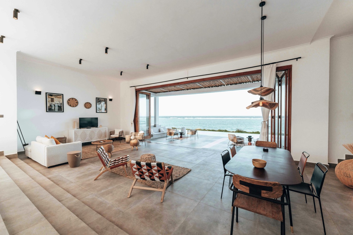 Spaziosa zona living arredata in stile moderno, con grandi porte scorrevoli che si aprono su una vista panoramica del mare