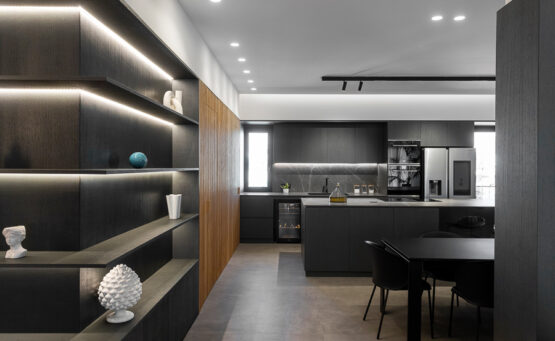 Elegante soggiorno e sala da pranzo moderni con arredi minimalisti neri, dettagli in legno e divano grigio chiaro, illuminati da luce naturale
